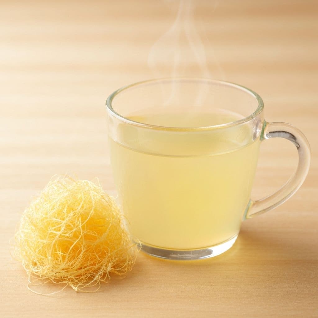 Staklena šolja blijedo žutog čaja od kukuruzne svile sa zlatnim svilenim nitima